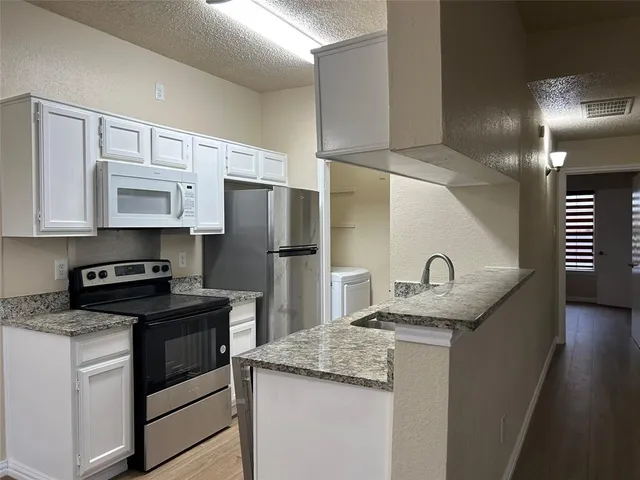 a kitchen with granite countertop a sink stove and refrigerator