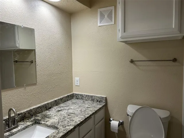 a bathroom with a granite countertop toilet and sink
