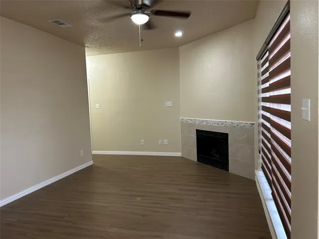 an empty room with wooden floor fireplace and windows