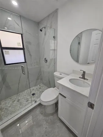 a bathroom with a granite countertop sink toilet and shower