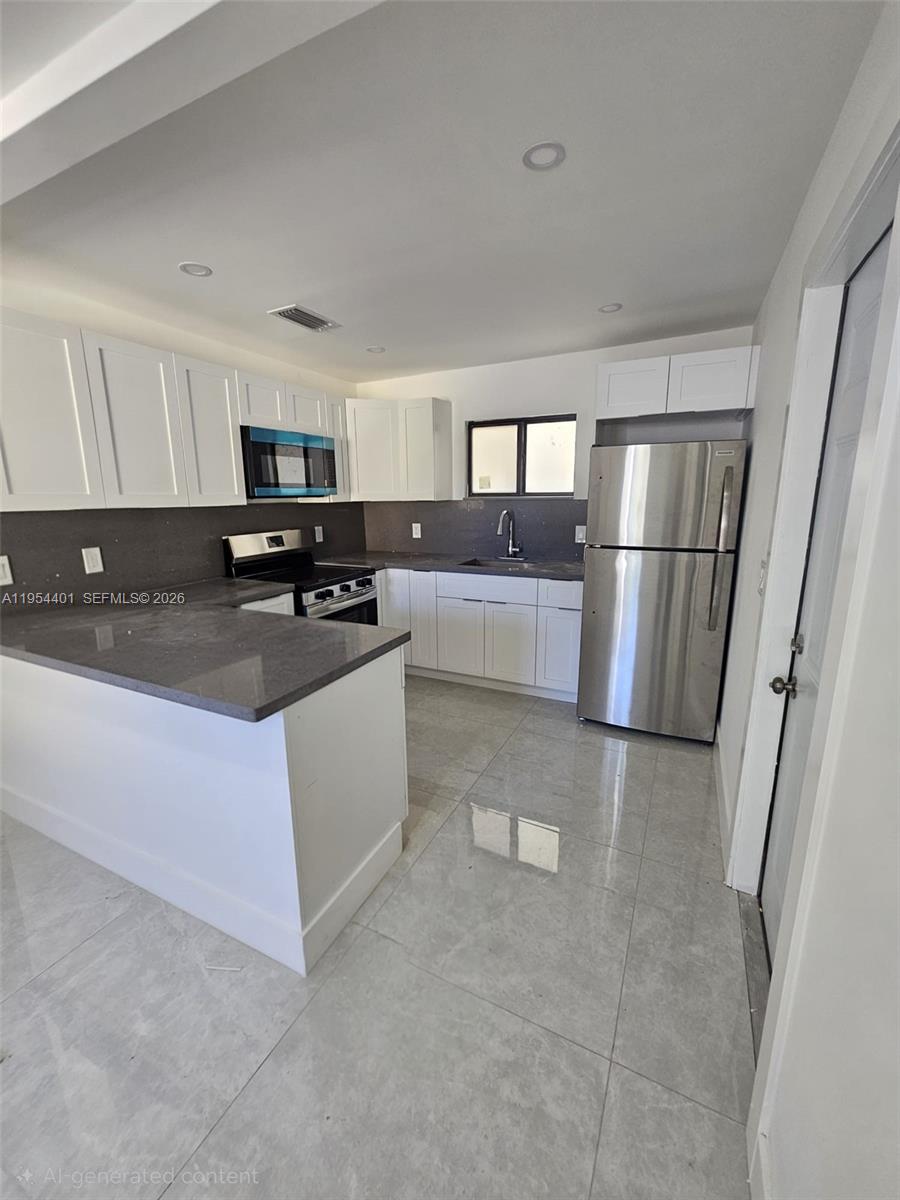 1148 Northwest 100th Street, Unit 2 Miami, FL 33150 - Photo 4 of 22 a kitchen with stainless steel appliances a refrigerator stove microwave and sink