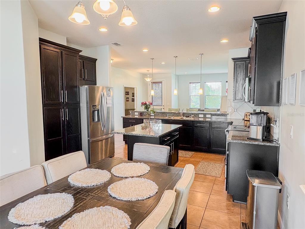 8607 Randal Park Boulevard Orlando, FL 32832 - Photo 18 of 51 a kitchen with stainless steel appliances kitchen island granite countertop a refrigerator a sink a stove a dining table and chairs