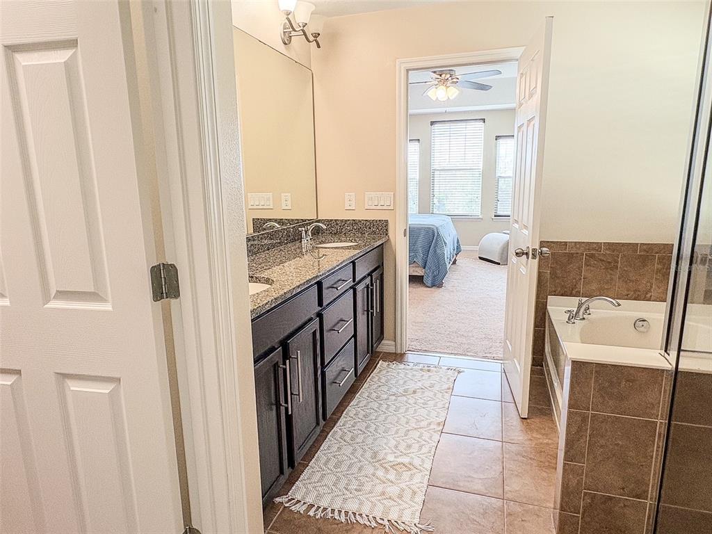 8607 Randal Park Boulevard Orlando, FL 32832 - Photo 33 of 51 a bathroom with a granite countertop sink a mirror and shower