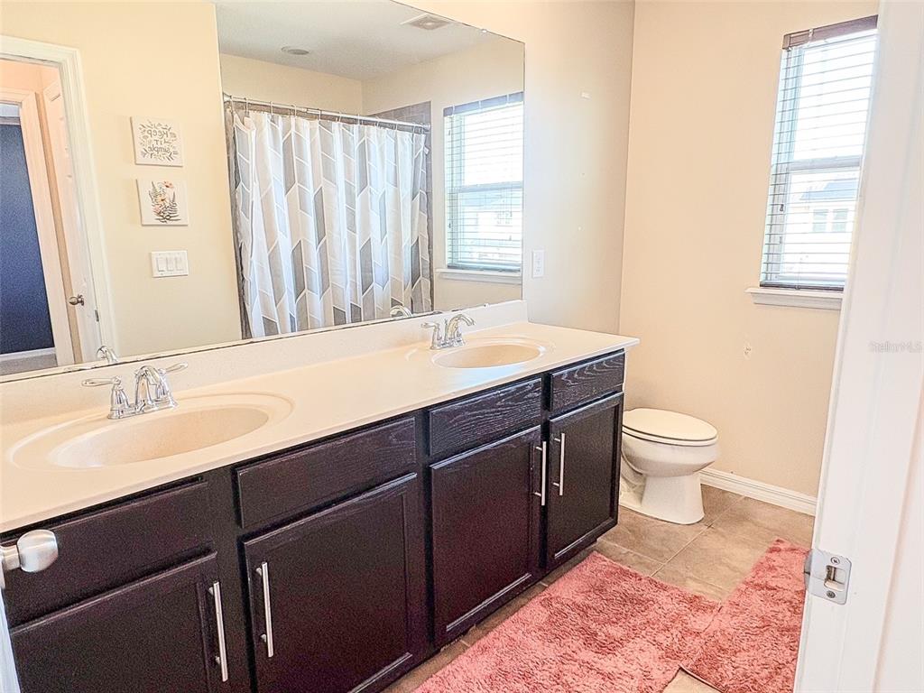 8607 Randal Park Boulevard Orlando, FL 32832 - Photo 39 of 51 a bathroom with a double vanity sink toilet and a mirror