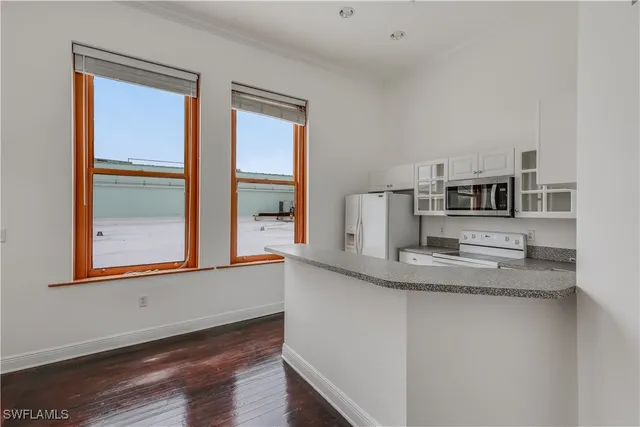 a living room with stainless steel appliances wooden floor and a large window