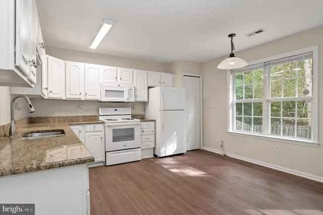 a kitchen with granite countertop white cabinets and white appliances