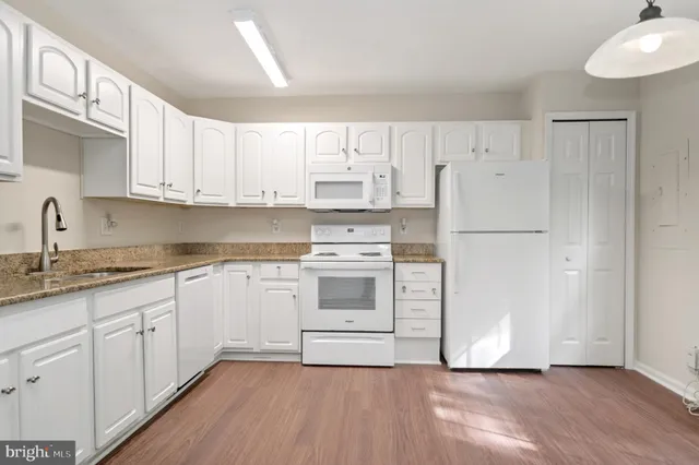 a kitchen with granite countertop white cabinets and white appliances