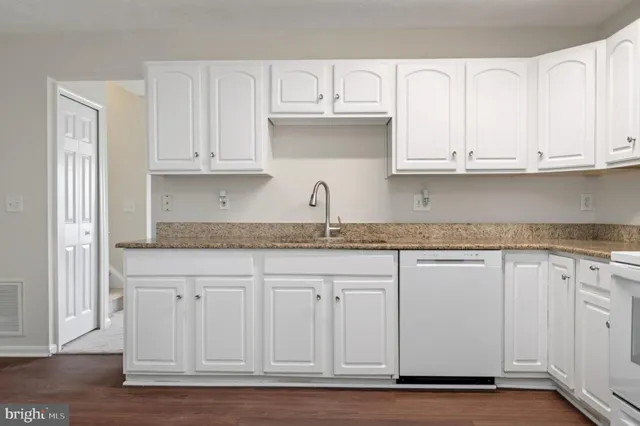 a kitchen with granite countertop white cabinets and a sink