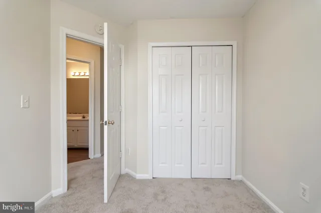 a view of an empty room with closet and a bathroom