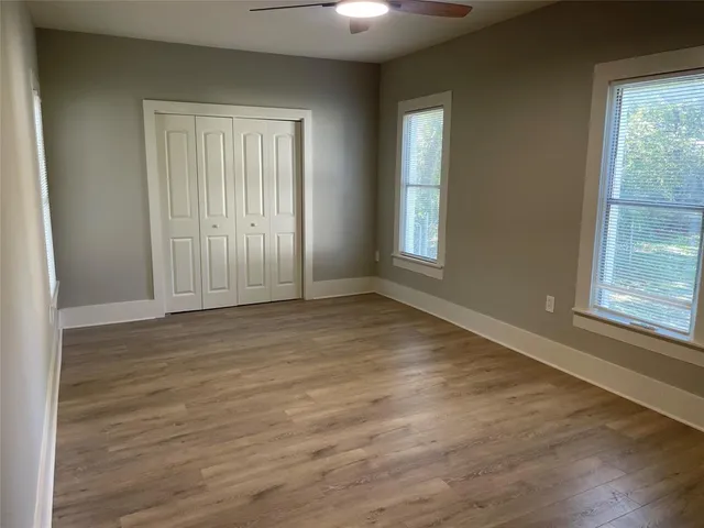 an empty room with wooden floor and windows