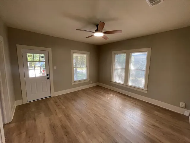a view of an empty room with wooden floor and a window