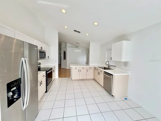 a large white kitchen with a stove a sink dishwasher and a refrigerator