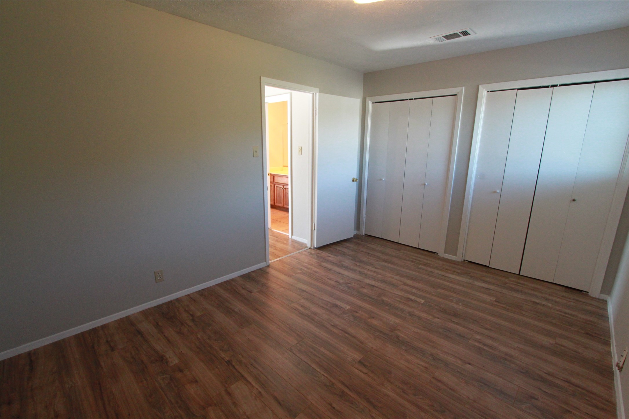 3904 Hudson Bend Road, Unit D Austin, TX 78734 - Photo 22 of 25 Unfurnished bedroom featuring two closets and dark wood-style flooring