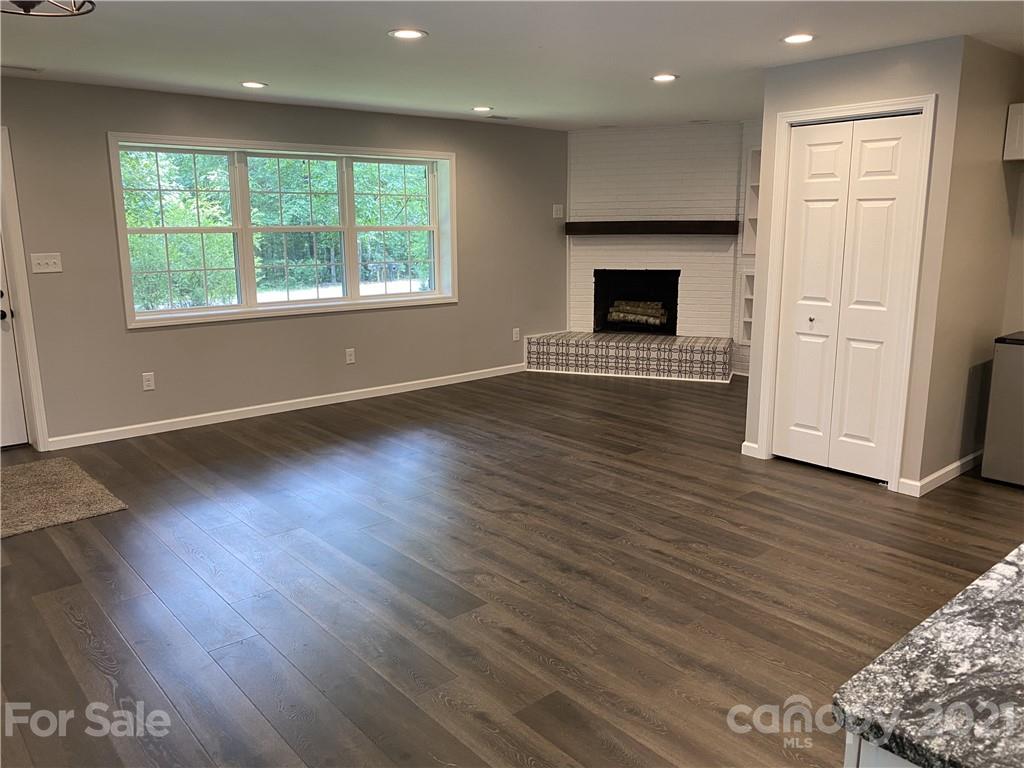 629 Thompson Road Rutherfordton, NC 28139 - Photo 4 of 10 an empty room with wooden floor fireplace and windows