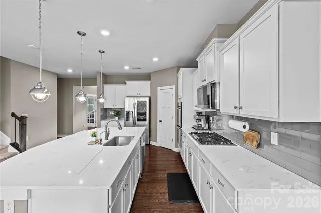 a large white kitchen with sink and stainless steel appliances