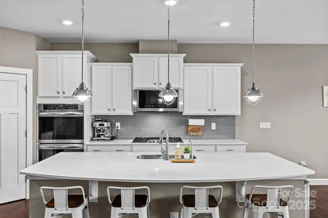 a kitchen with kitchen island granite countertop a sink a stove and refrigerator