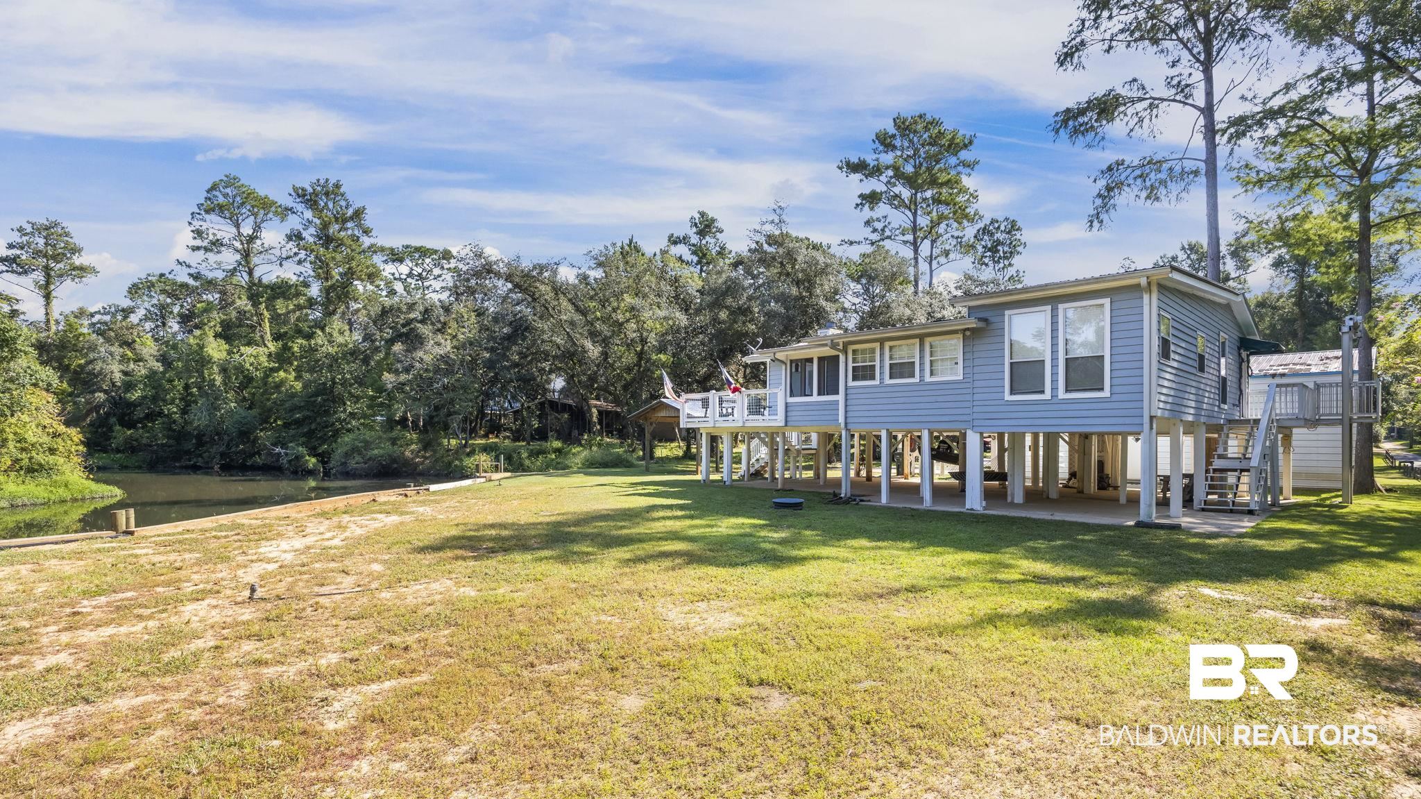 12855 Woodhaven Dairy Road West Silverhill, AL 36576 - Photo 1 of 27 Back of property with a lawn, a patio, stairway, and a deck with water view