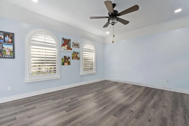 an empty room with windows and fan