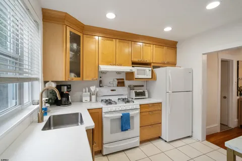 a kitchen with a refrigerator a stove top oven cabinets and a window