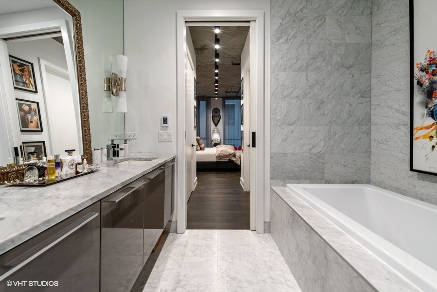 111 South Peoria Street, Unit 506 Chicago, IL 60607 - Photo 19 of 24 a en suite bathroom with a granite countertop tub sink and glass door