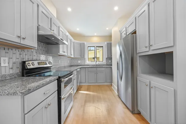 a kitchen with granite countertop a sink a counter top space stainless steel appliances and cabinets