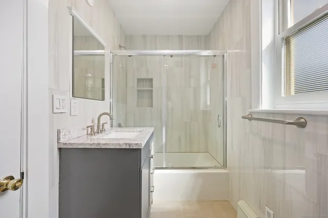 a bathroom with a granite countertop sink a mirror a vanity and shower