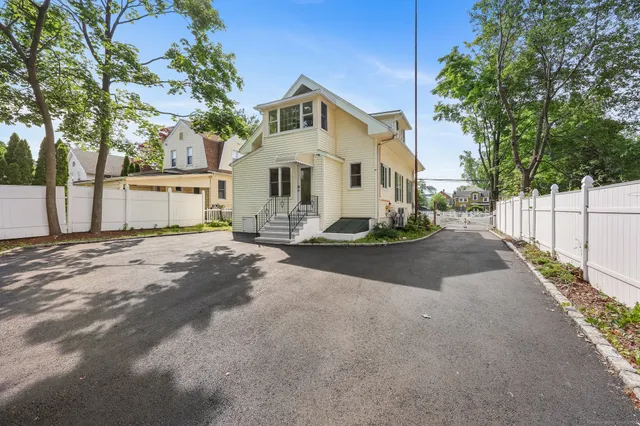 a view of a white house with a big yard and large tree