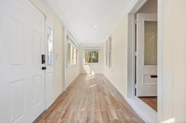 a view of a hallway with wooden floor and a bathroom