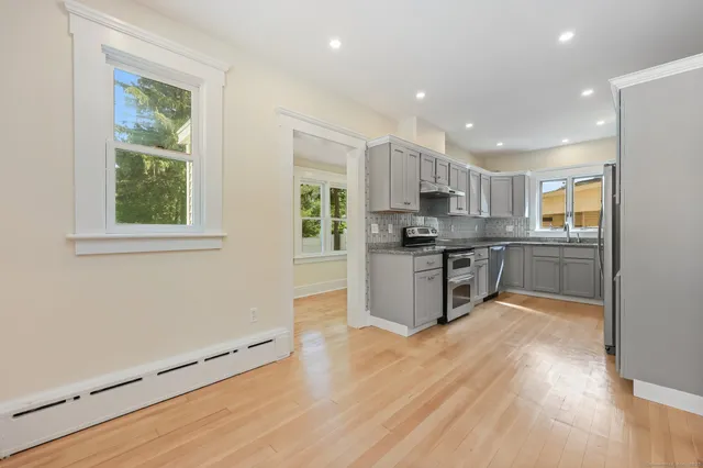 a kitchen with stainless steel appliances granite countertop a stove top oven a sink dishwasher and a refrigerator with wooden floor