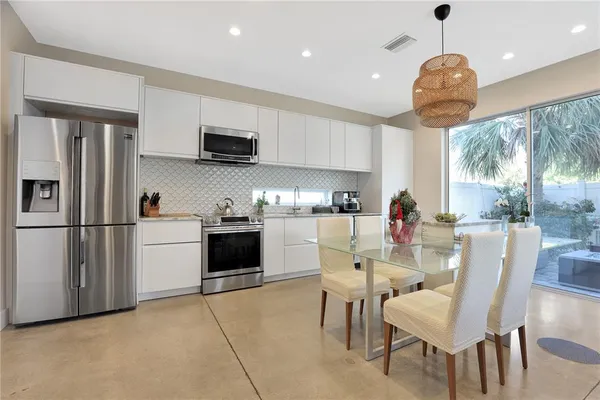 a kitchen with stainless steel appliances granite countertop a refrigerator a stove a sink dishwasher and a dining table with wooden floor