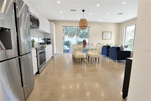 a view of a dining room with furniture a kitchen and chandelier