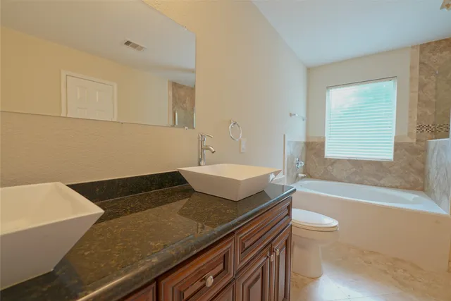 a bathroom with a granite countertop sink and a bathtub