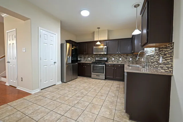 a kitchen with stainless steel appliances granite countertop a stove a sink and a refrigerator