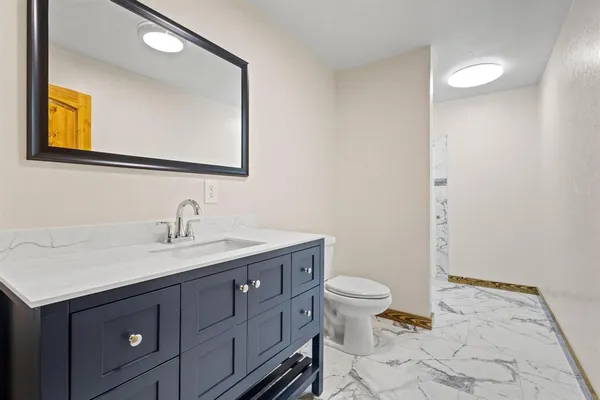 a bathroom with a granite countertop sink a toilet and mirror