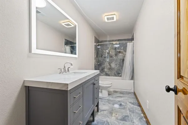 a bathroom with a sink a toilet a mirror and shower