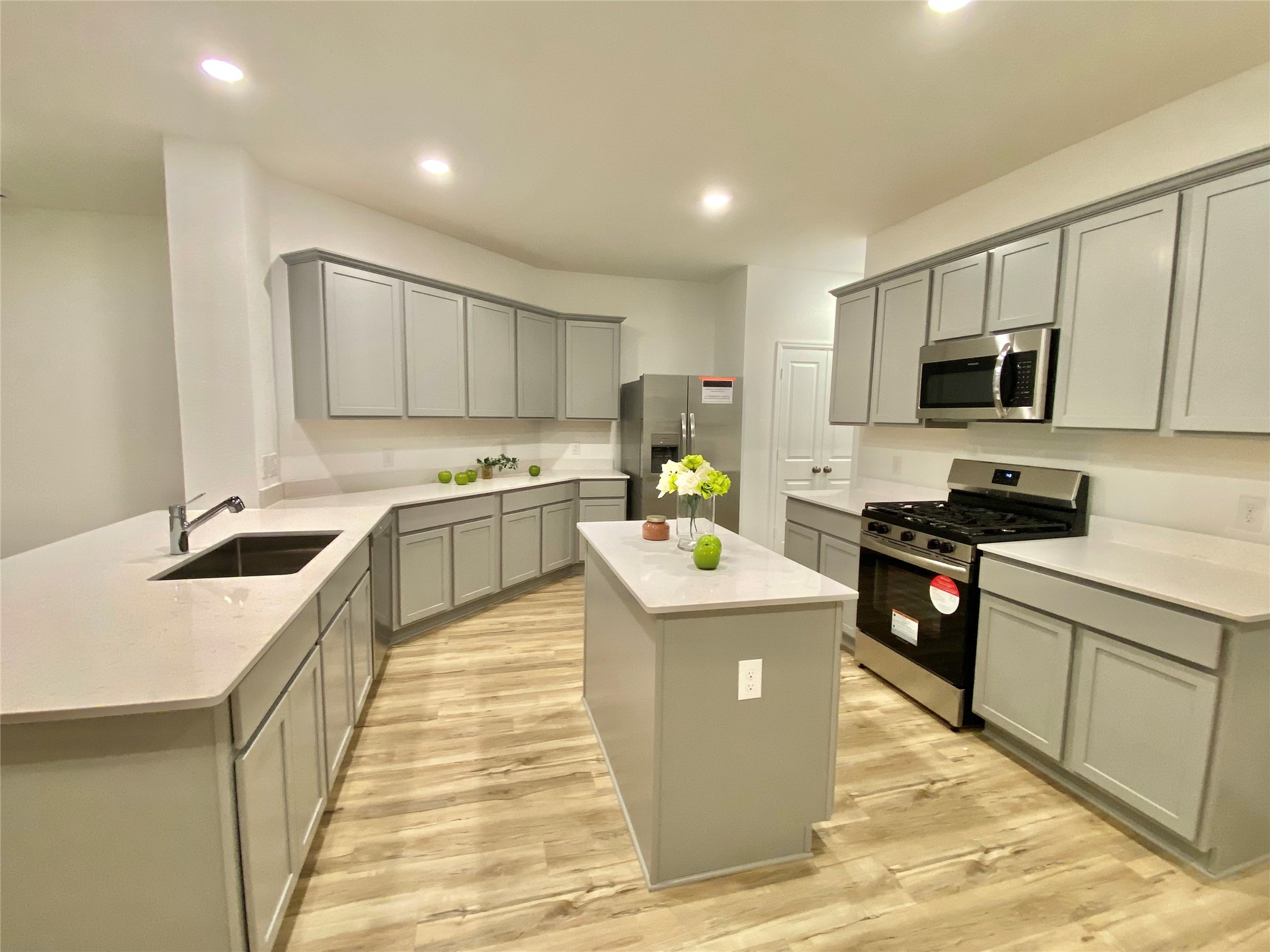 3724 Moss Hl Road Rosenberg, TX 77469 - Photo 11 of 29 This kitchen features modern gray cabinetry, stainless steel appliances, and a central island. The space is well-lit with recessed lighting and has light wood flooring, giving it a bright and contemporary feel.