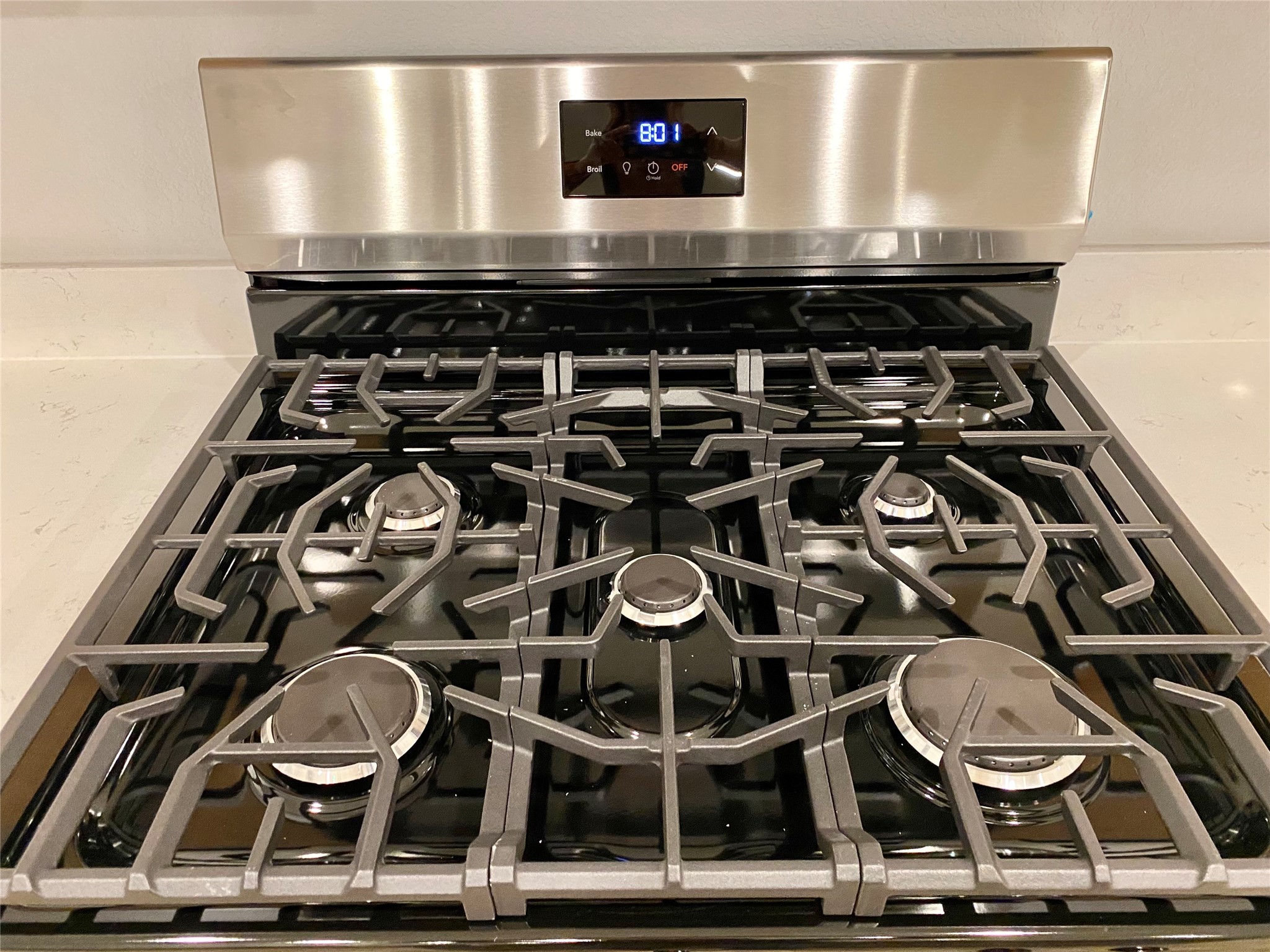 3724 Moss Hl Road Rosenberg, TX 77469 - Photo 12 of 29 This photo features a modern stainless steel gas stove with five burners and digital controls, set against a clean, neutral backsplash, ideal for a contemporary kitchen.