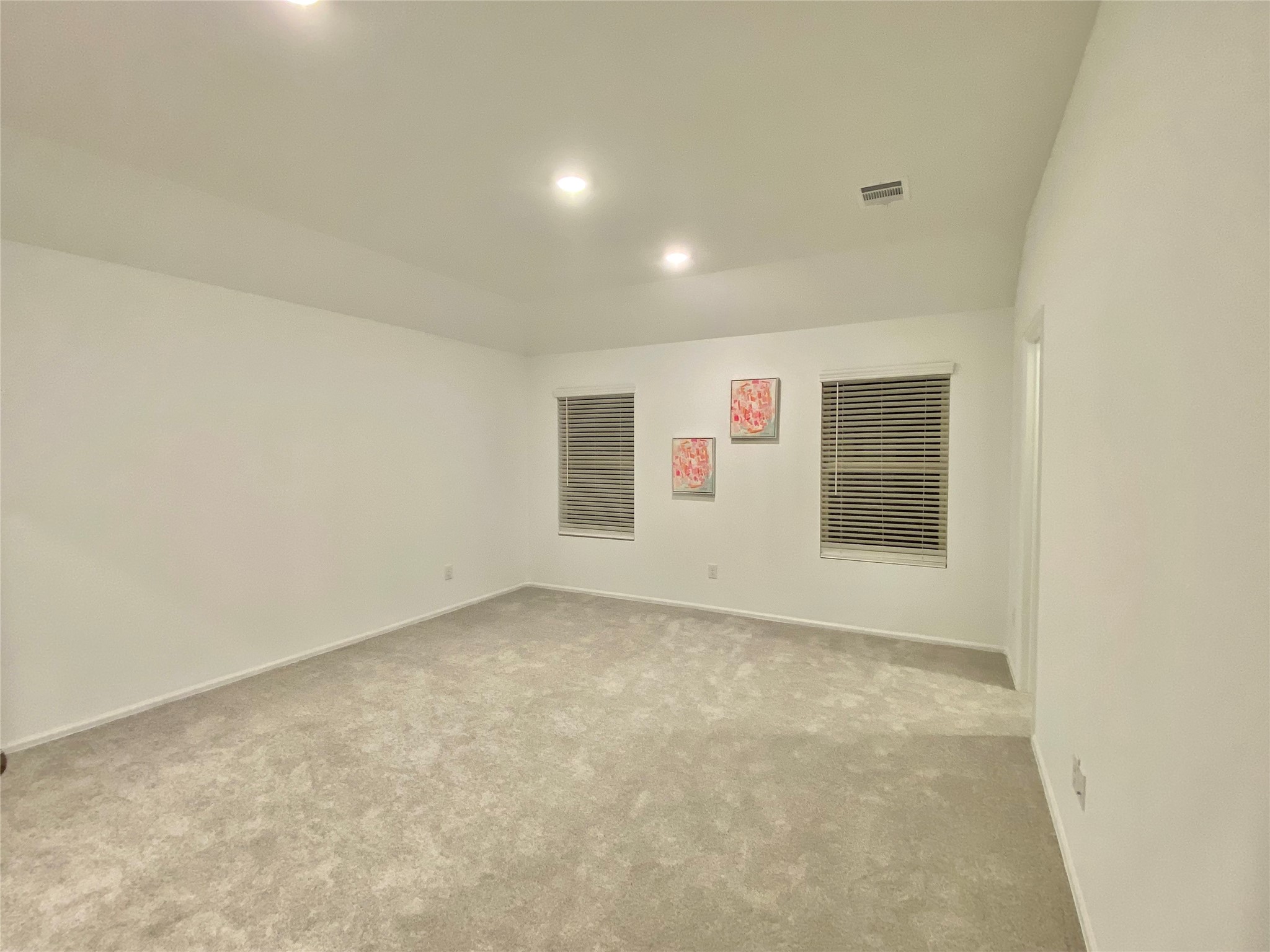 3724 Moss Hl Road Rosenberg, TX 77469 - Photo 14 of 29 This room features a neutral palette with soft carpeting, recessed lighting, and two windows with blinds. It has a spacious feel, accented by three modern art pieces on one wall.