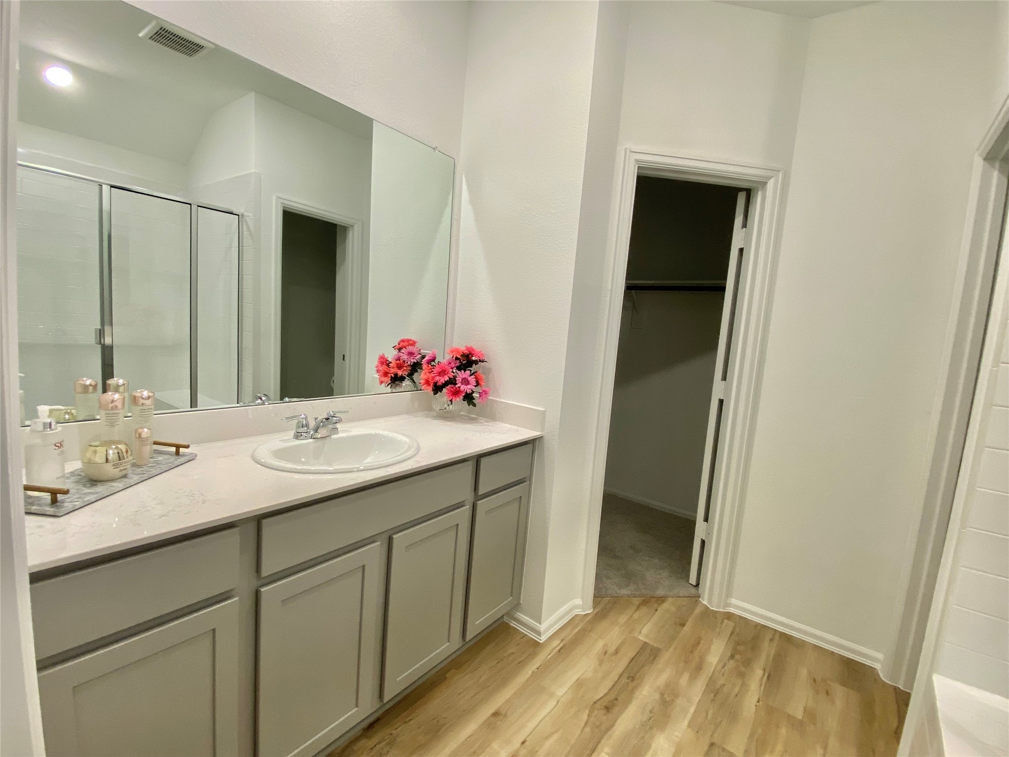 3724 Moss Hl Road Rosenberg, TX 77469 - Photo 15 of 29 Modern bathroom with sleek cabinetry, large mirror, and light wood flooring. It features a spacious walk-in closet and a glass-enclosed shower.