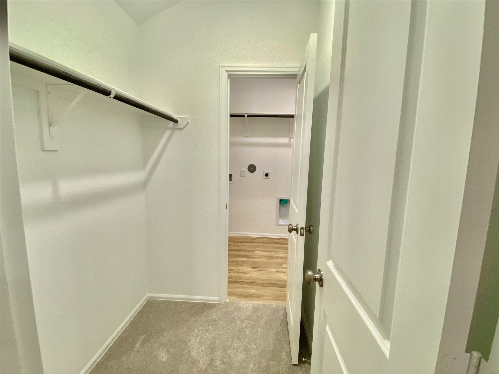 3724 Moss Hl Road Rosenberg, TX 77469 - Photo 19 of 29 This photo shows a small walk-in closet with a hanging rod and shelf, leading into a laundry area with hardwood flooring.