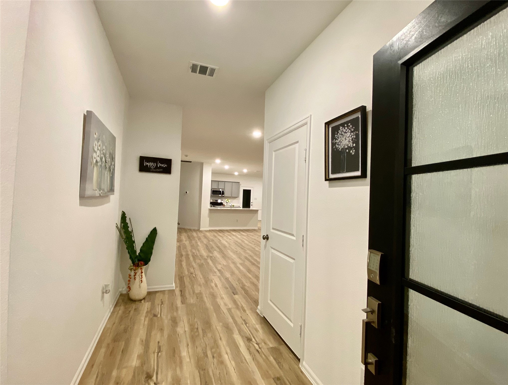 3724 Moss Hl Road Rosenberg, TX 77469 - Photo 2 of 29 This photo showcases a modern entryway with wood-style flooring, neutral walls, and recessed lighting. It leads into an open-concept kitchen area, creating a welcoming and spacious atmosphere.