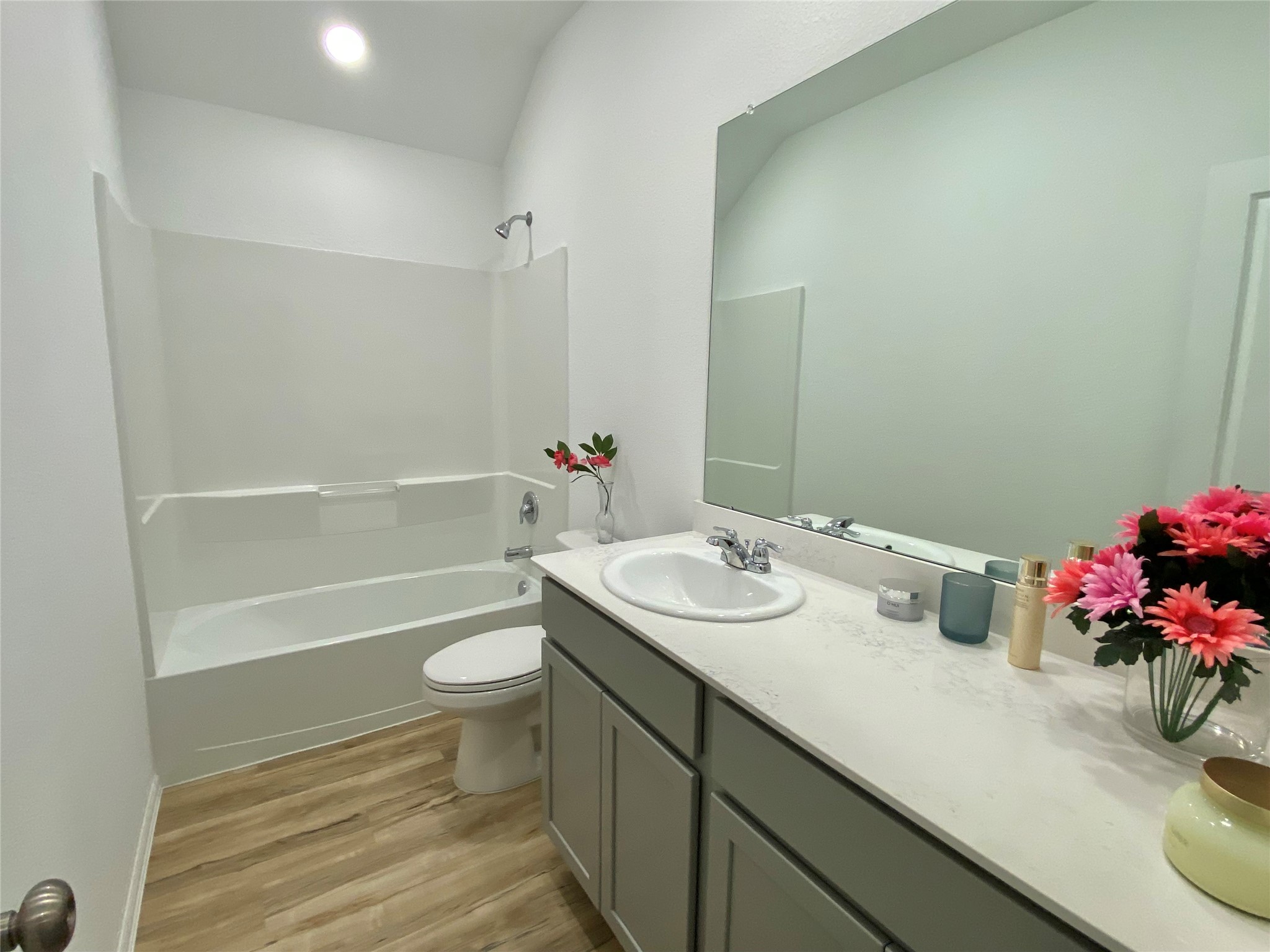 3724 Moss Hl Road Rosenberg, TX 77469 - Photo 22 of 29 This bathroom features a clean, modern design with a spacious vanity, large mirror, and a combination shower-tub. The bright space includes sleek fixtures and wood-style flooring, providing a fresh and inviting atmosphere.