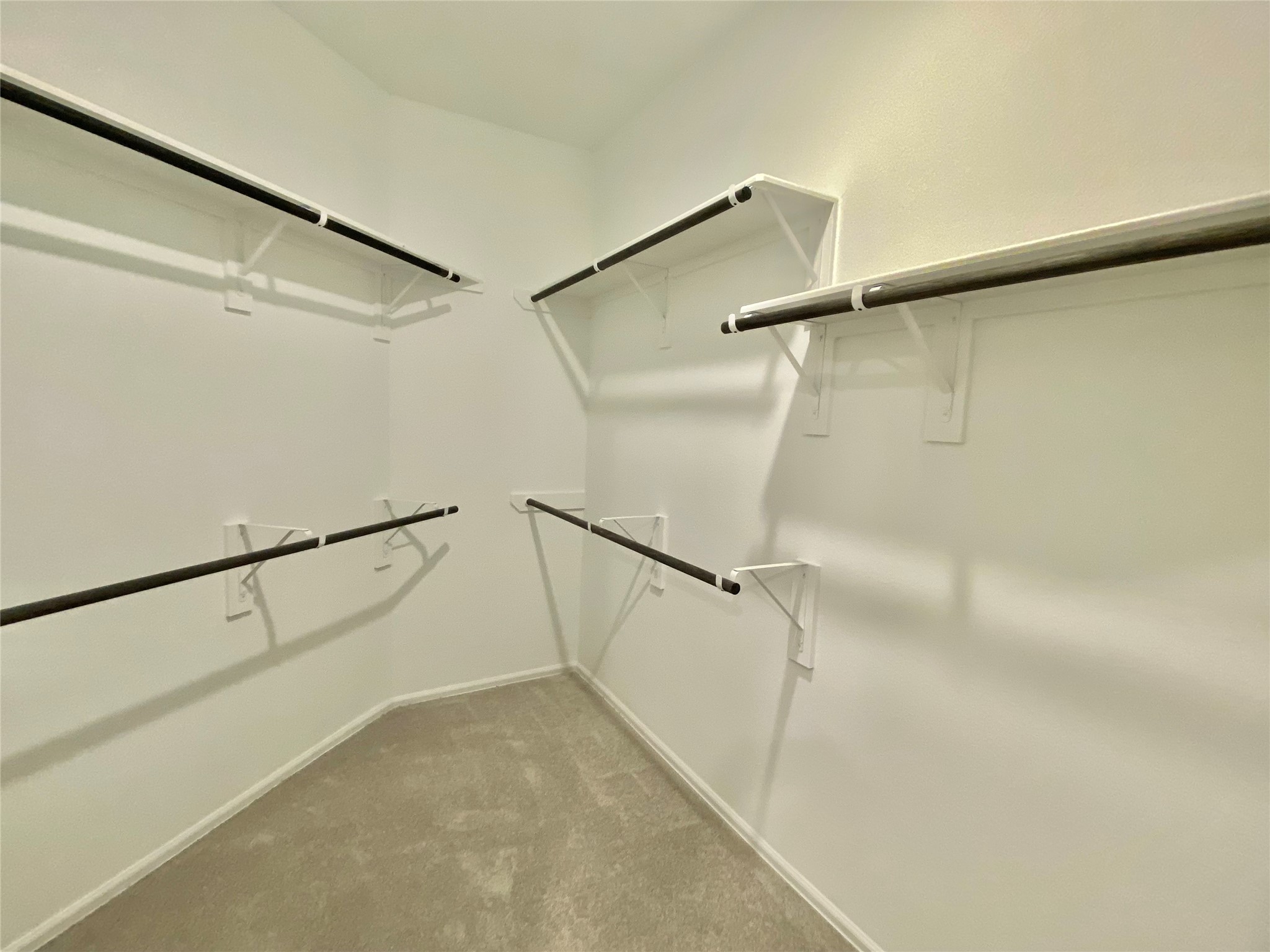 3724 Moss Hl Road Rosenberg, TX 77469 - Photo 25 of 29 This is a spacious walk-in closet with multiple hanging rods, providing ample storage for clothing and accessories. The neutral color scheme and carpeting create a clean and inviting atmosphere.