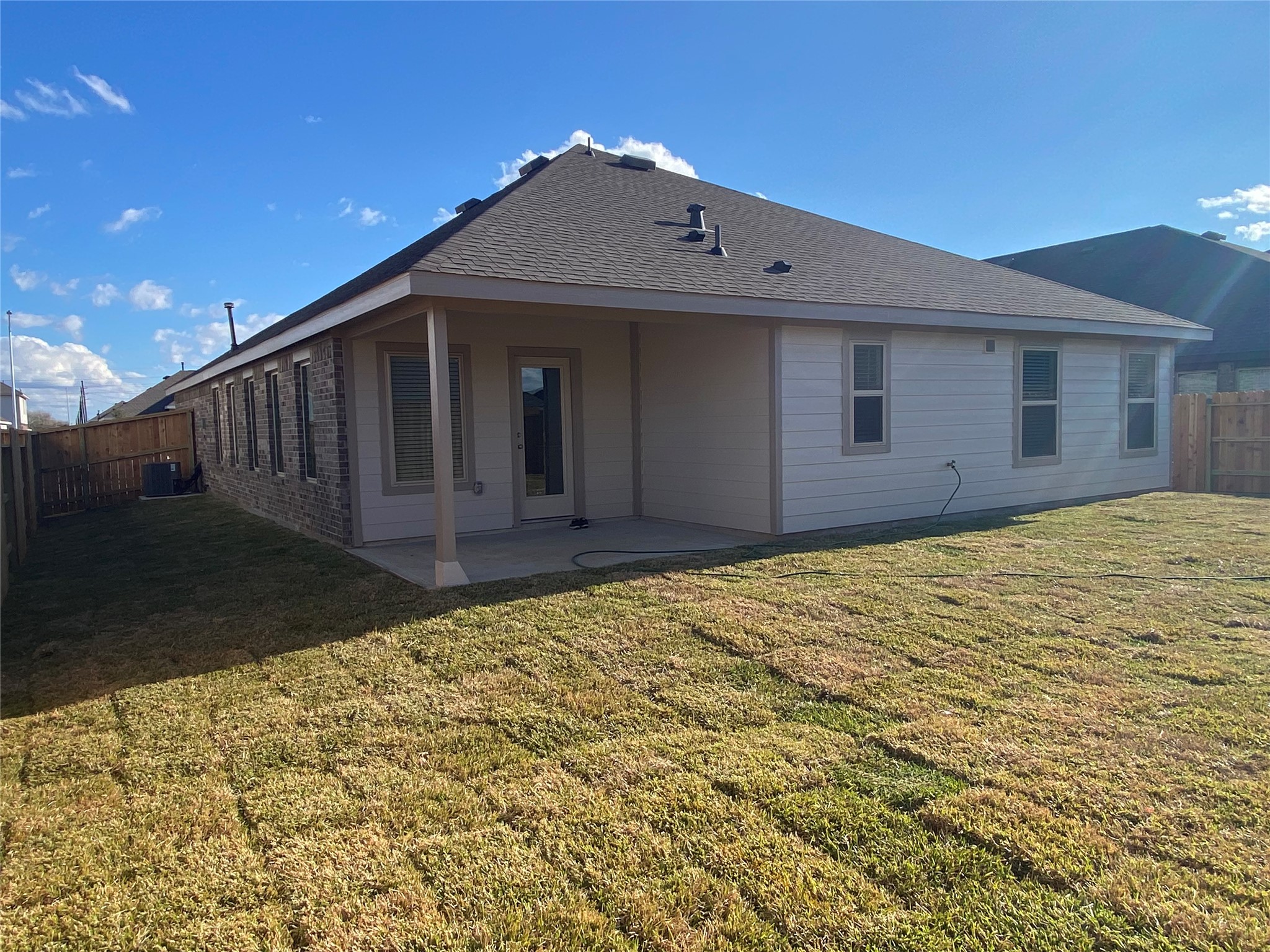 3724 Moss Hl Road Rosenberg, TX 77469 - Photo 29 of 29 This photo showcases the backyard of a single-story home with a covered patio. The house features a combination of brick and siding, and is surrounded by a fenced yard with a well-maintained lawn, offering a private outdoor space.