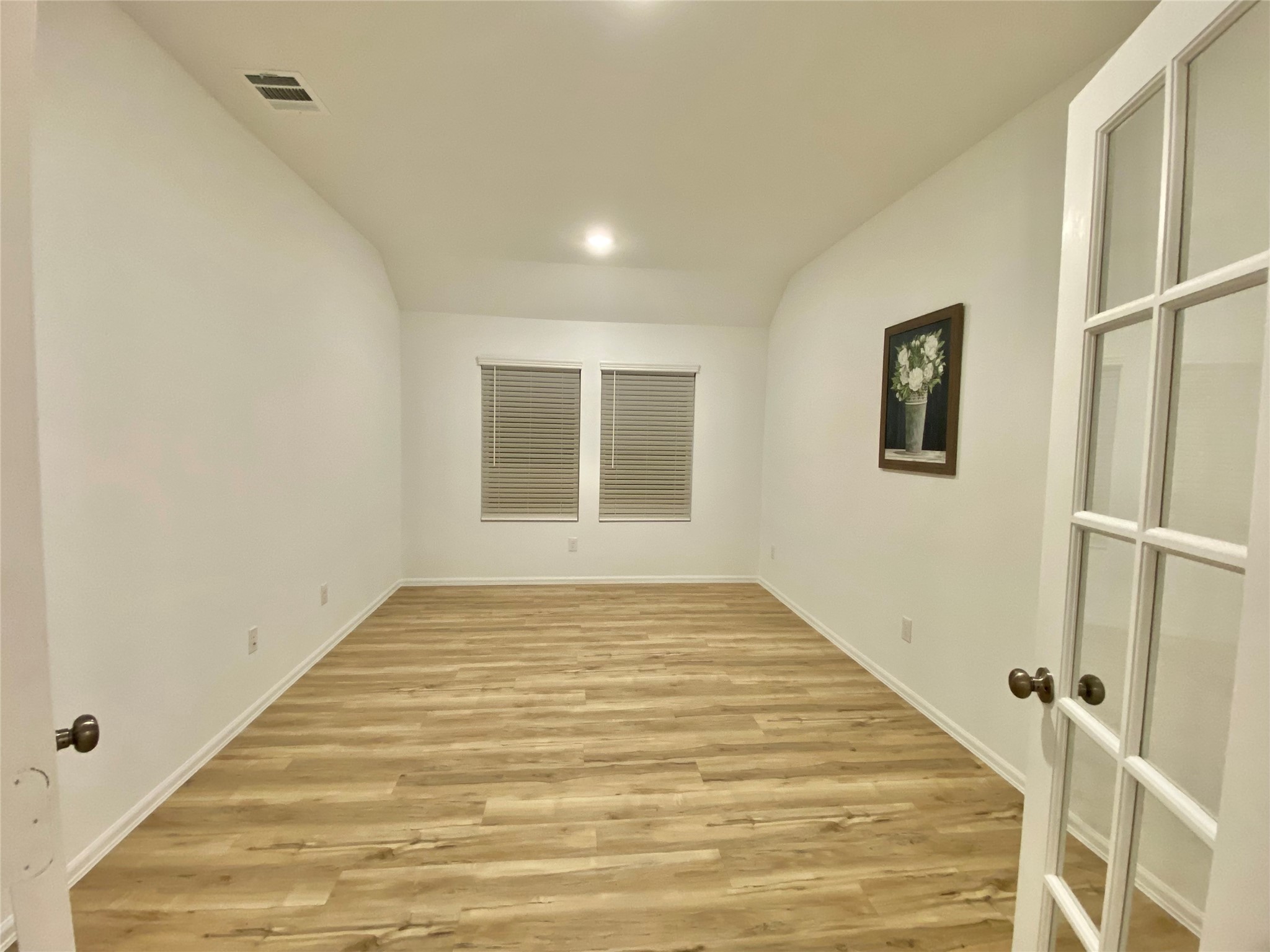 3724 Moss Hl Road Rosenberg, TX 77469 - Photo 6 of 29 This room features a spacious layout with light wood flooring and neutral white walls. It has two windows with blinds, recessed lighting, and a decorative wall piece. A set of glass French doors provides an elegant entrance. Ideal for a home office or extra bedroom.