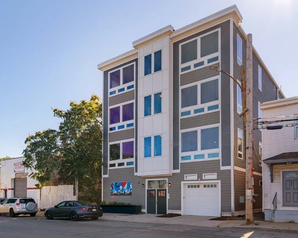 243 Condor Street, Unit 4 Boston, MA 02128 - Photo 13 of 13 a front view of a building with lot of cars and trees