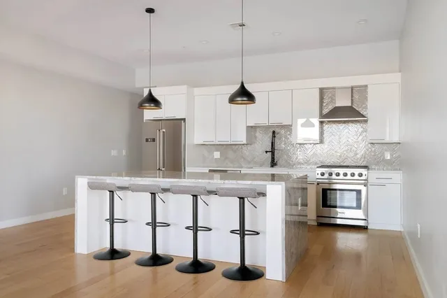 a kitchen with stainless steel appliances granite countertop a stove a sink and a wooden floor