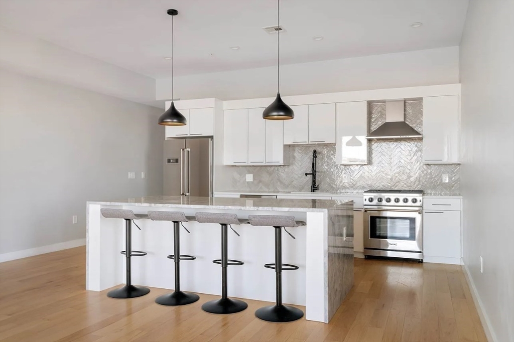 243 Condor Street, Unit 4 Boston, MA 02128 - Photo 2 of 13 a kitchen with stainless steel appliances granite countertop a stove a sink and a wooden floor