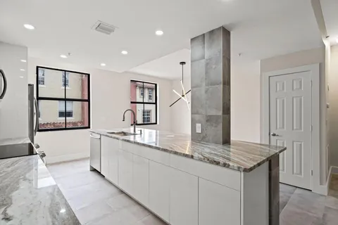 a large kitchen with kitchen island a large counter top space and windows