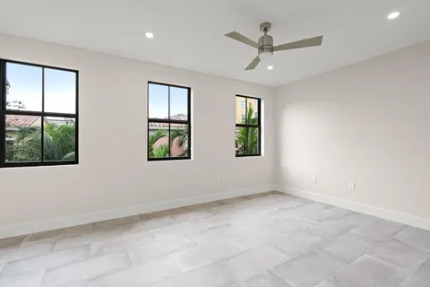 an empty room with windows and ceiling fan